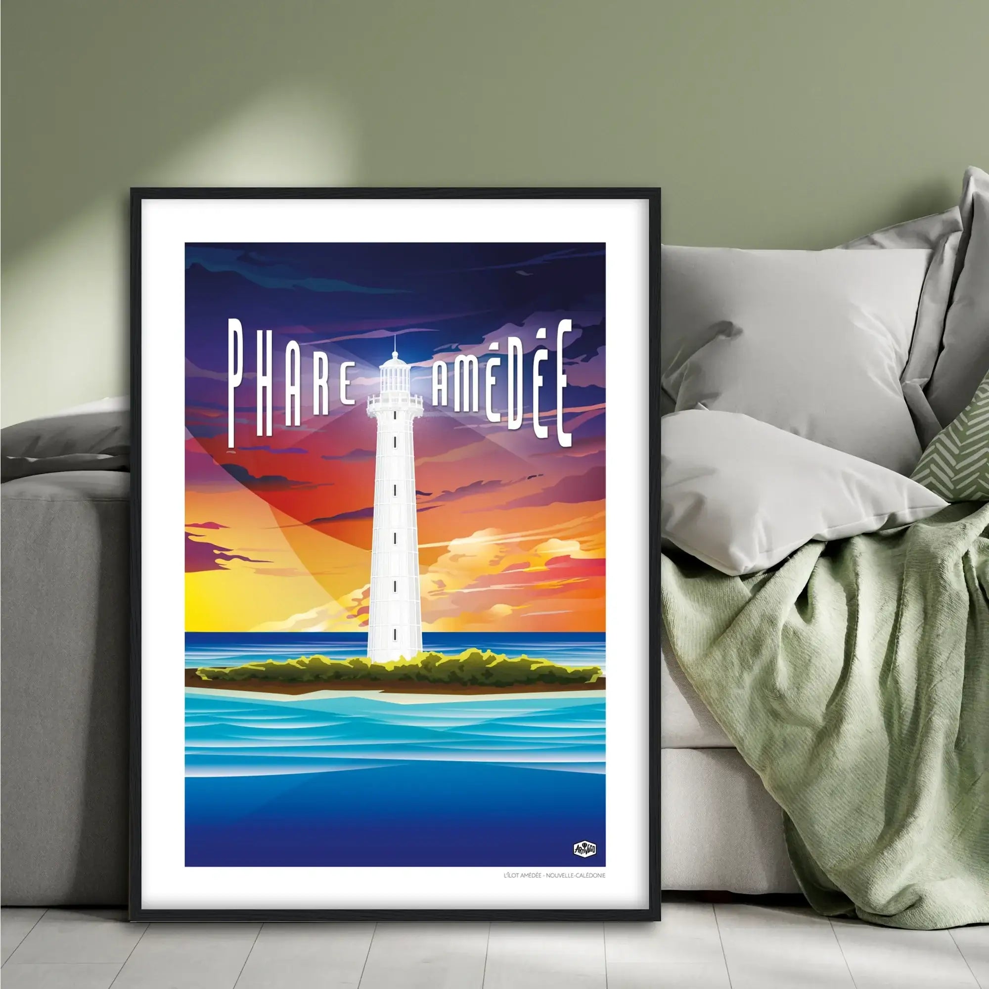 Affiche Nouvelle-Calédonie « Le phare Amédée », format 50×70 cm avec cadre noir, posée contre un lit dans une chambre à la décoration douce et naturelle