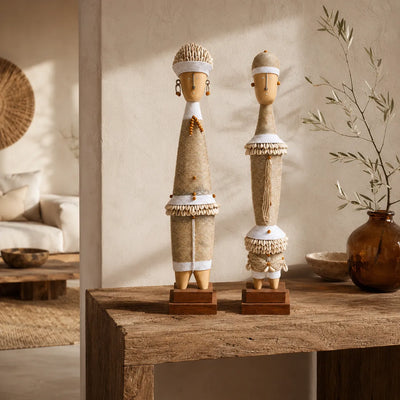 Couple de statues décoratives blanches d’inspiration Namji, posé sur une console en bois dans un intérieur bohème chic aux matières naturelles