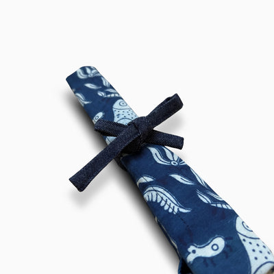 Détail du porte-couverts roulé – tissu indigo imprimé oiseaux – gros plan sur le nœud en jean